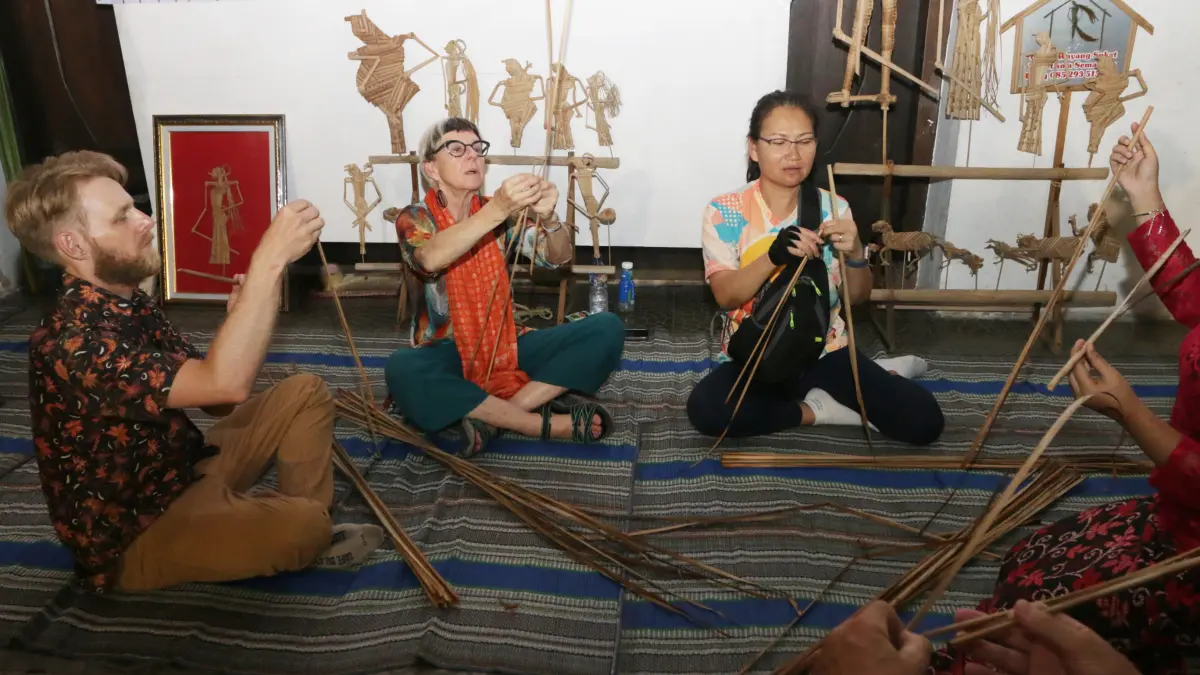 Peserta sepeda tua internasional dari berbagai negara belajar membuat Wayang Suket di halaman Gedung Oudetrap, Kota Lama Semarang, Kamis (28/5/2026). (Nur Chamim/Jawa Pos Radar Semarang)