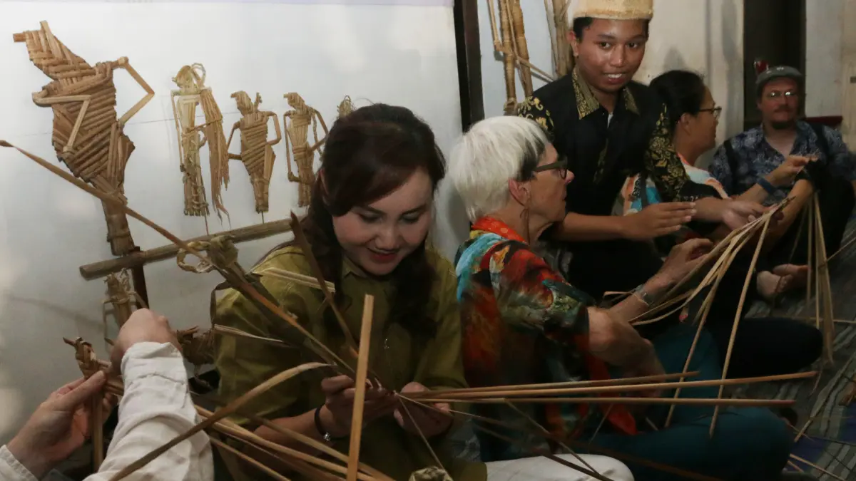 Peserta sepeda tua internasional dari berbagai negara belajar membuat Wayang Suket di halaman Gedung Oudetrap, Kota Lama Semarang, Kamis (28/5/2026). (Nur Chamim/Jawa Pos Radar Semarang)