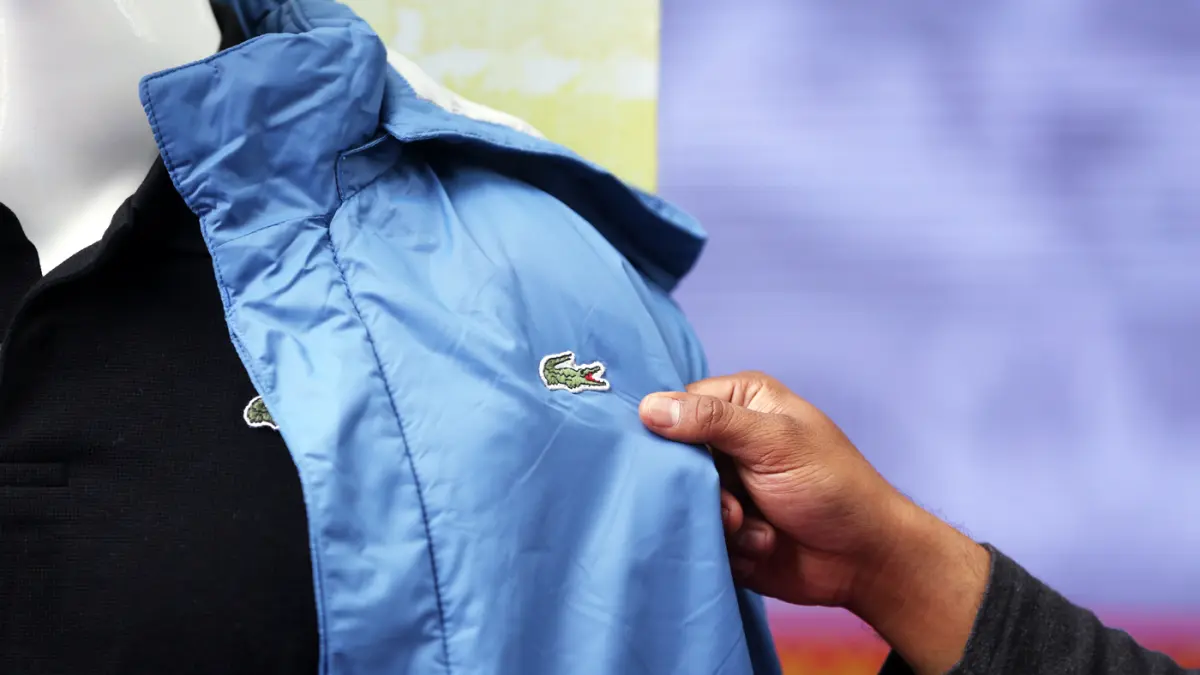Petugas menunjukkan baju bermerk Lacoste palsu sebelum dimusnahkan di kantor Direktorat Jenderal Kekayaan Intelektual (DJKI) pada Kementerian Hukum (Kemenkum) di Jakarta, Senin (22/6/2026). (Dery Ridwansah/ JawaPos.com)
