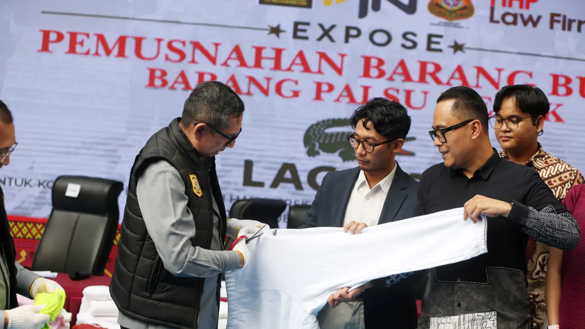Petugas menunjukkan baju bermerk Lacoste palsu sebelum dimusnahkan di kantor Direktorat Jenderal Kekayaan Intelektual (DJKI) pada Kementerian Hukum (Kemenkum) di Jakarta, Senin (22/6/2026). (Dery Ridwansah/ JawaPos.com)