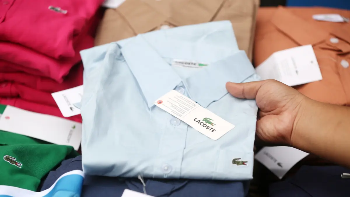 Petugas menunjukkan baju bermerk Lacoste palsu sebelum dimusnahkan di kantor Direktorat Jenderal Kekayaan Intelektual (DJKI) pada Kementerian Hukum (Kemenkum) di Jakarta, Senin (22/6/2026). (Dery Ridwansah/ JawaPos.com)