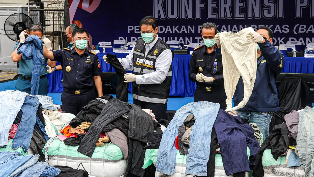 Menteri Keuangan Purbaya Yudhi Sadewa (kedua kiri) dan Dirjen Bea dan Cukai Djaka Budhi Utama (kiri) menunjukkan pakaian bekas impor ilegal (balpres) saat konferensi pers penindakan peti kemas pakaian bekas ilegal di Buffer Area TPS CDC Pelabuhan Tanjung
