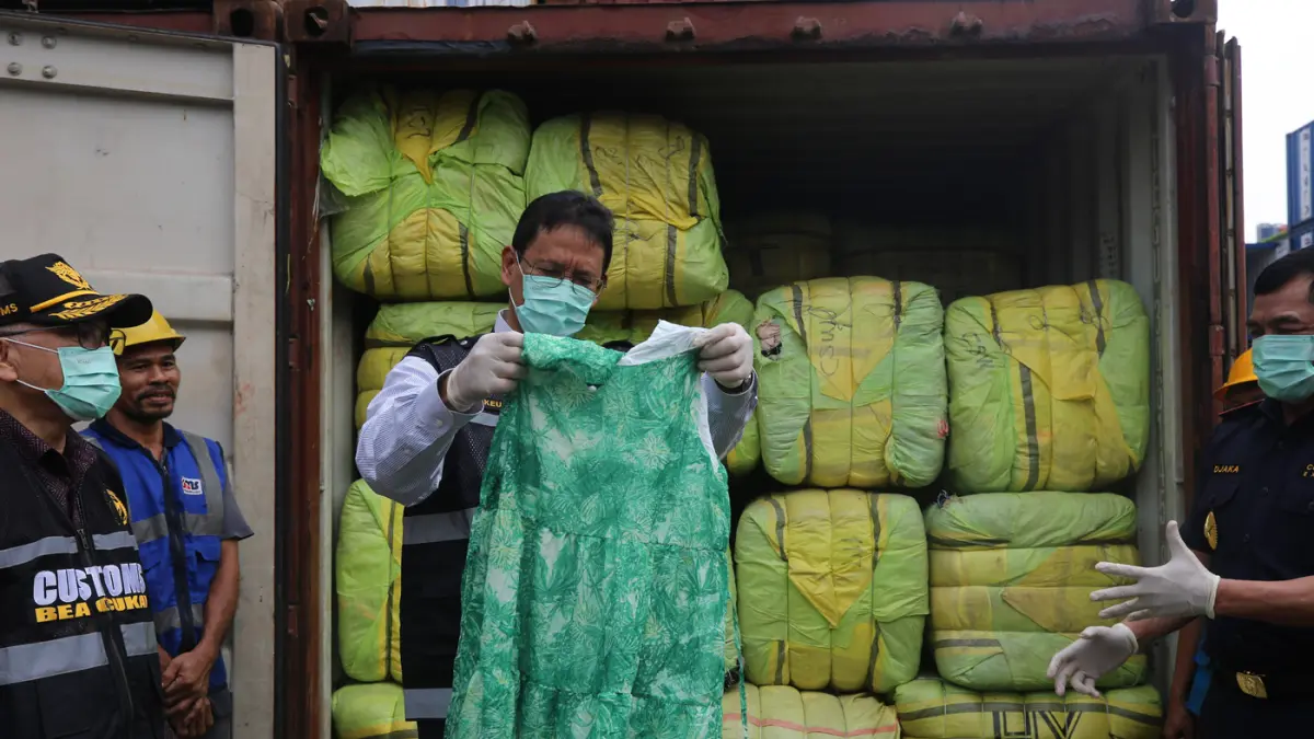 Menteri Keuangan Purbaya Yudhi Sadewa menunjukkan pakaian bekas impor ilegal (balpres) saat konferensi pers penindakan peti kemas pakaian bekas ilegal di Buffer Area TPS CDC Pelabuhan Tanjung Priok, Jakarta, Selasa (23/6/2026). (Salman Toyibi/Jawa Pos)
