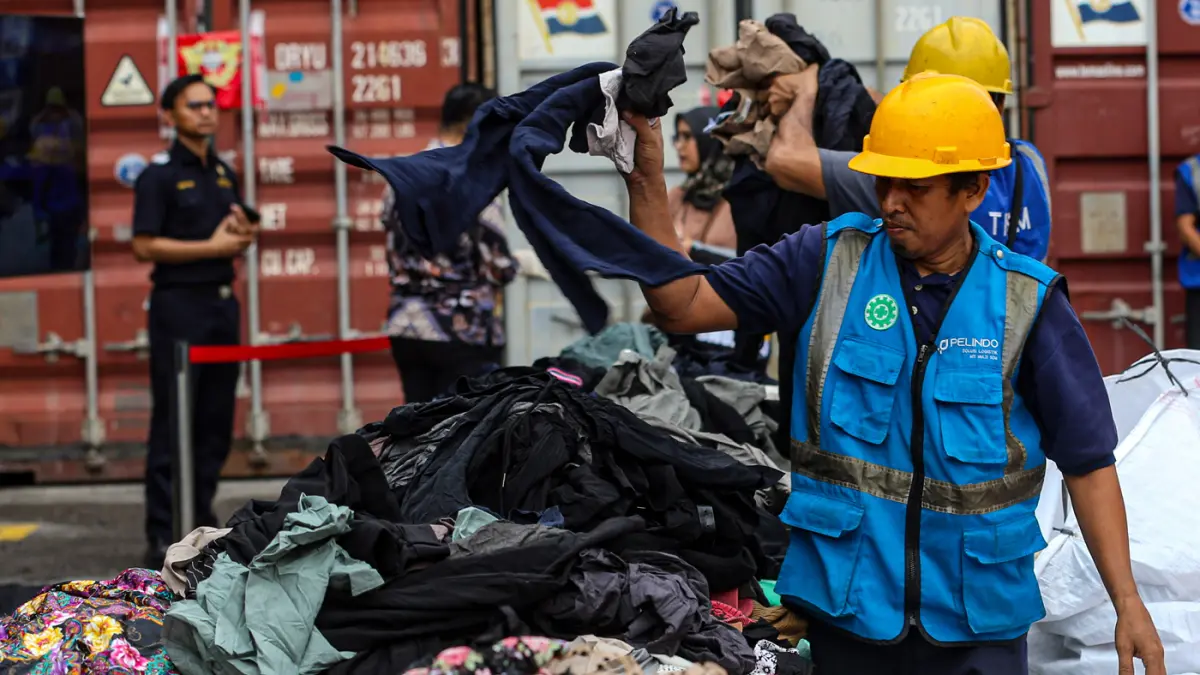 Petugas menata barang saat konferensi pers penindakan peti kemas pakaian bekas ilegal di Buffer Area TPS CDC Pelabuhan Tanjung Priok, Jakarta, Selasa (23/6/2026). (Salman Toyibi/Jawa Pos)