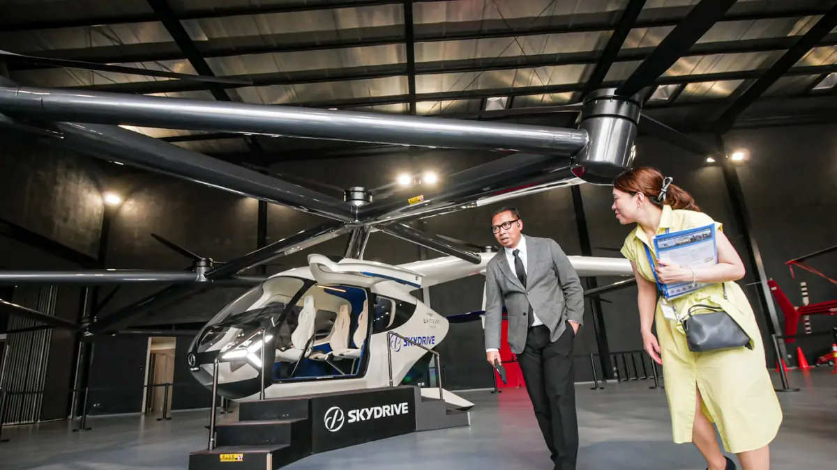 Sejumlah pengunjung melihat pesawat listrik lepas landas dan mendarat vertikal (eVTOL) buatan SkyDrive di Cerngkareng Heliport, Bandara Soekarno-Hatta, Kota Tangerang, Selasa (23/06/2026). (Hanung Hambara/Jawa Pos)