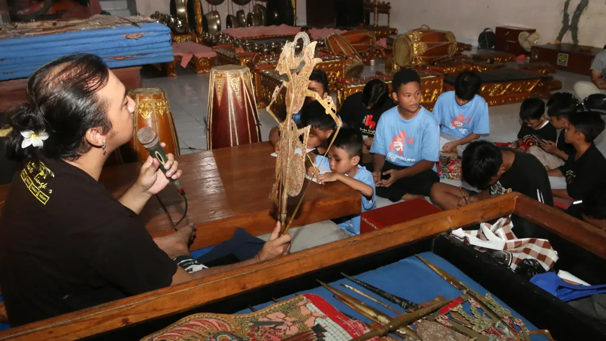 Instruktur mengajari anak-anak tentang tokoh pewayangan saat pelatihan seni karawitan dan pedalangan di Sindhu Laras Bocah, Semarang, Jawa Tengah, Minggu (21/6/2026). (Nur Chamim/ Jawa Pos Radar Semarang)