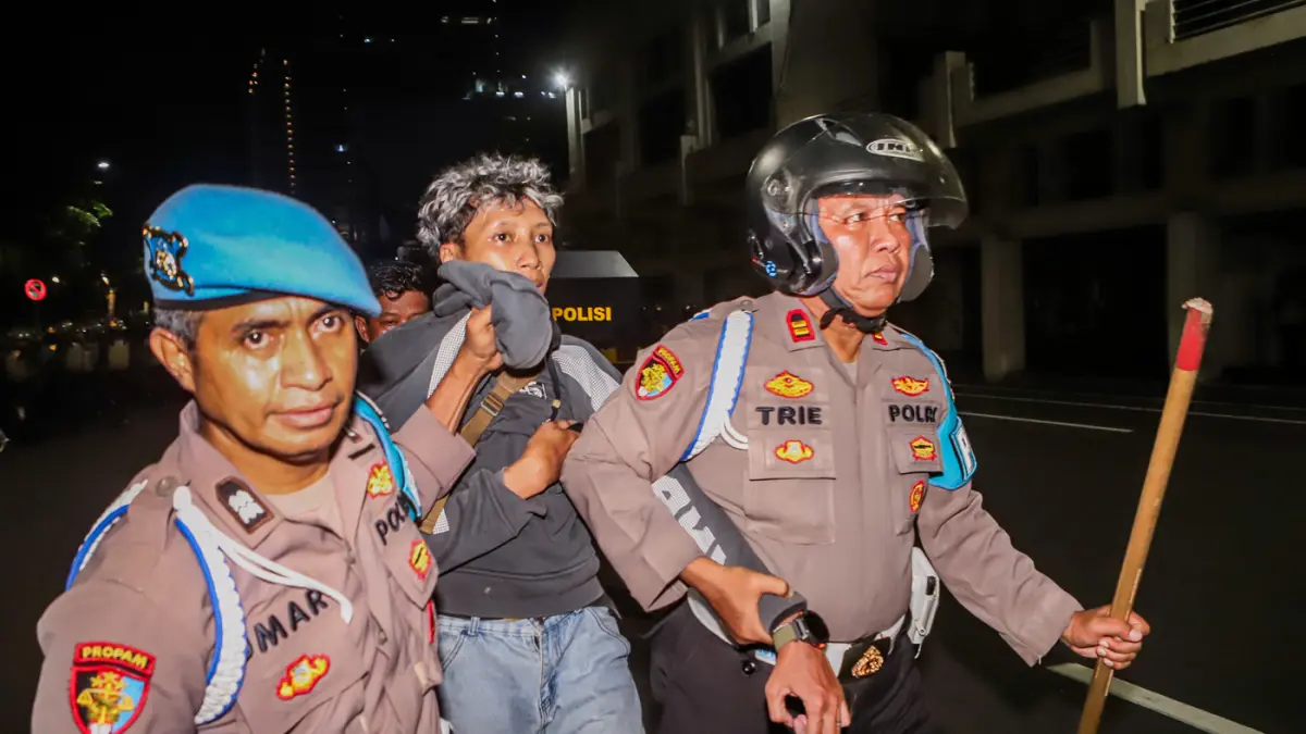 Petugas kepolisian menangkap sejunalh massa aksi yang diduga melakukan tindakan kerusuahan usai mengkritisi kebijakan pemerintah salah satunya program MBG di Gedung Negera Grahadi, Jalan Gubernur Suryo, Surabaya, Jawa Timur, Jumat (26/6/2026). (Riana Seti