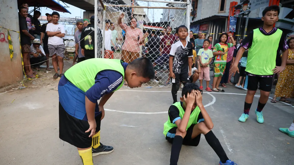 Anak-anak mengikuti pertandingan Turnamen Sepak Bola Liga Aspal U-13 di lapangan sederhana kawasan permukiman padat pinggir rel RT 09/RW 08, Menteng Jaya, Jakarta, Sabtu (27/6/2026). (Dery Ridwansah/ JawaPos.com)