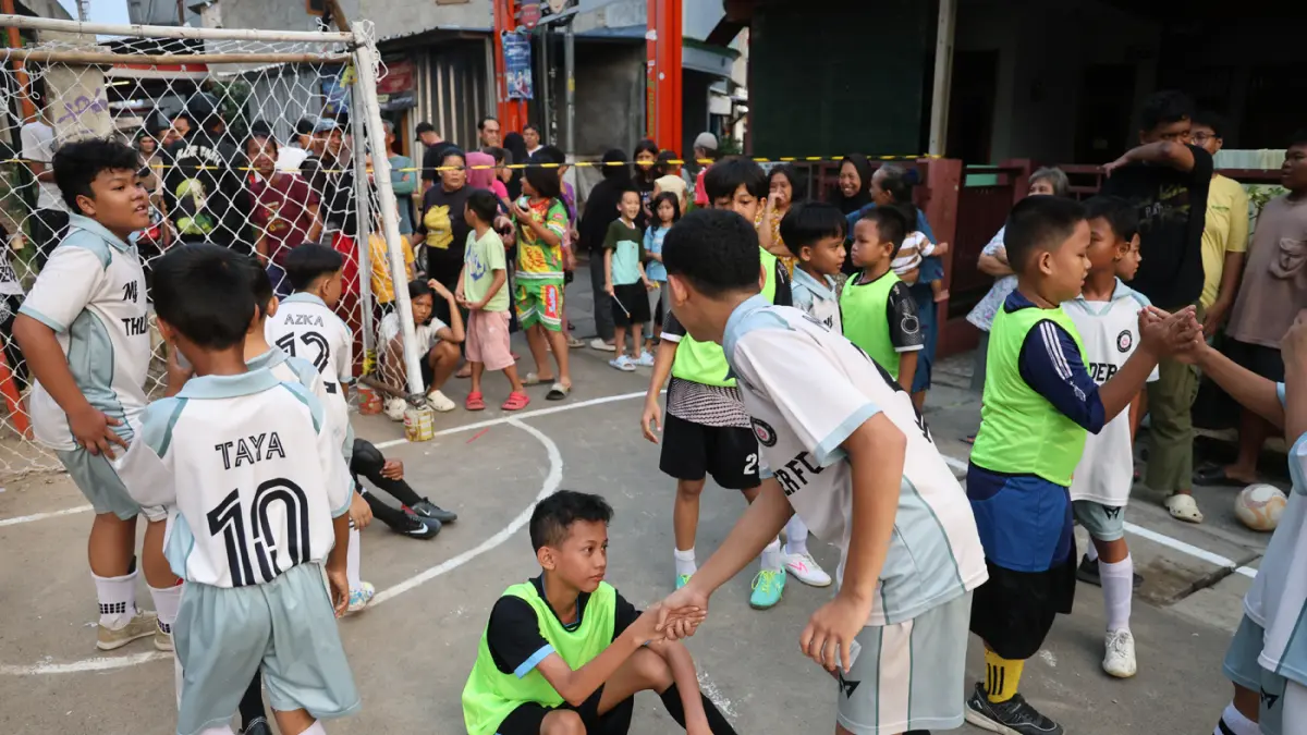 Anak-anak mengikuti pertandingan Turnamen Sepak Bola Liga Aspal U-13 di lapangan sederhana kawasan permukiman padat pinggir rel RT 09/RW 08, Menteng Jaya, Jakarta, Sabtu (27/6/2026). (Dery Ridwansah/ JawaPos.com)