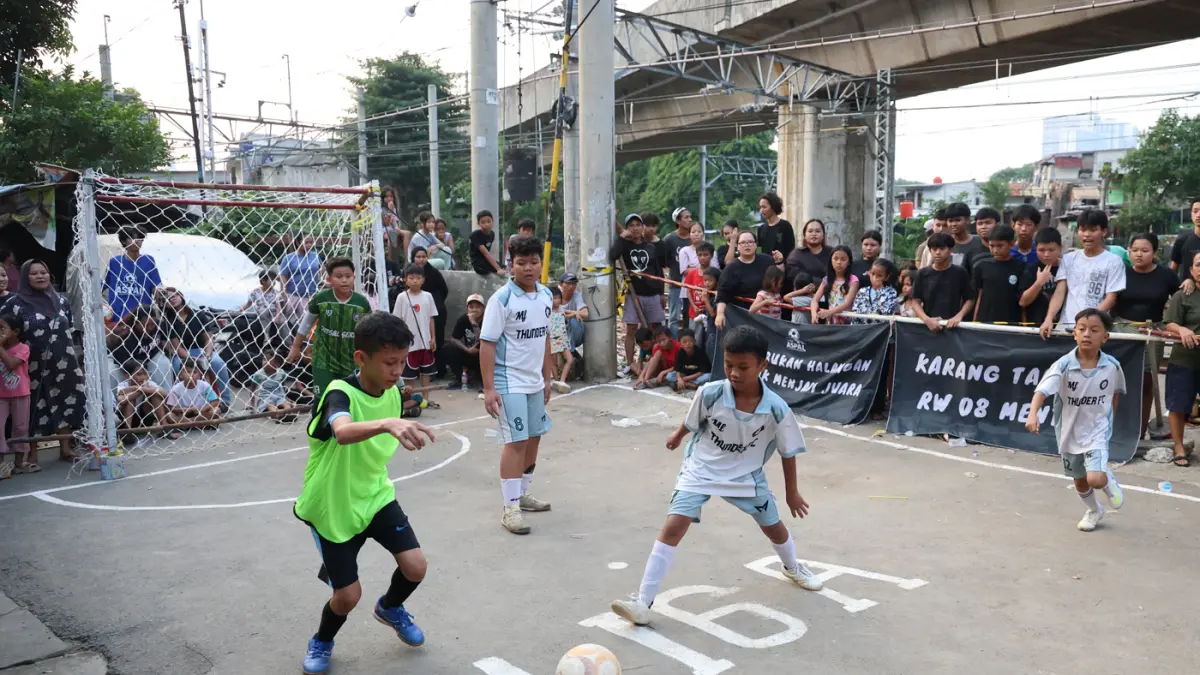 Suasana Pertandingan Turnamen Sepak Bola Liga Aspal U-13 di lapangan sederhana kawasan permukiman padat pinggir rel RT 09/RW 08, Menteng Jaya, Jakarta, Sabtu (27/6/2026). (Dery Ridwansah/ JawaPos.com)