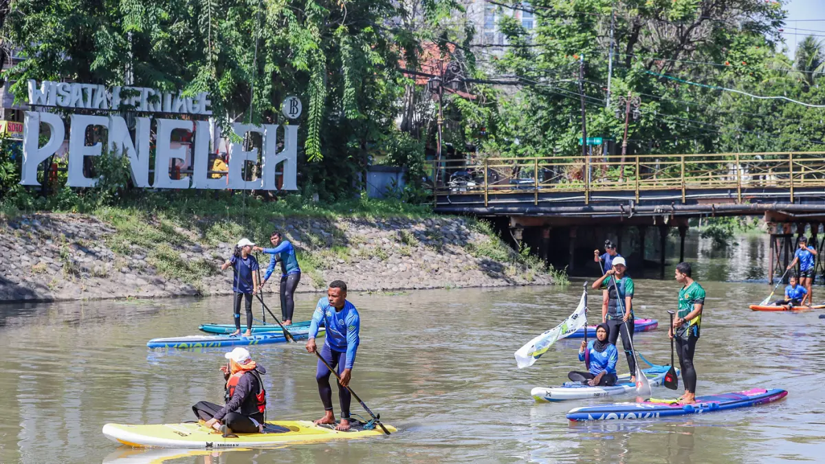 Peserta kompetisi stand up paddle melintas di Sungai Kalimas Kawasan Peneleh, Minggu (28/6/2026). (Riana Setiawan/Jawa Pos)