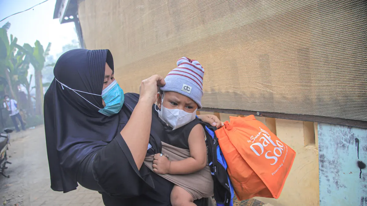 Sejumlah warga beraktifitas ditengah asap kebakaran TPA Jatiwaringin di Desa Tanjakan Mekar, Rajeg, Tangerang, Jumat (03/07/3026). (Hanung Hambara/Jawa Pos)