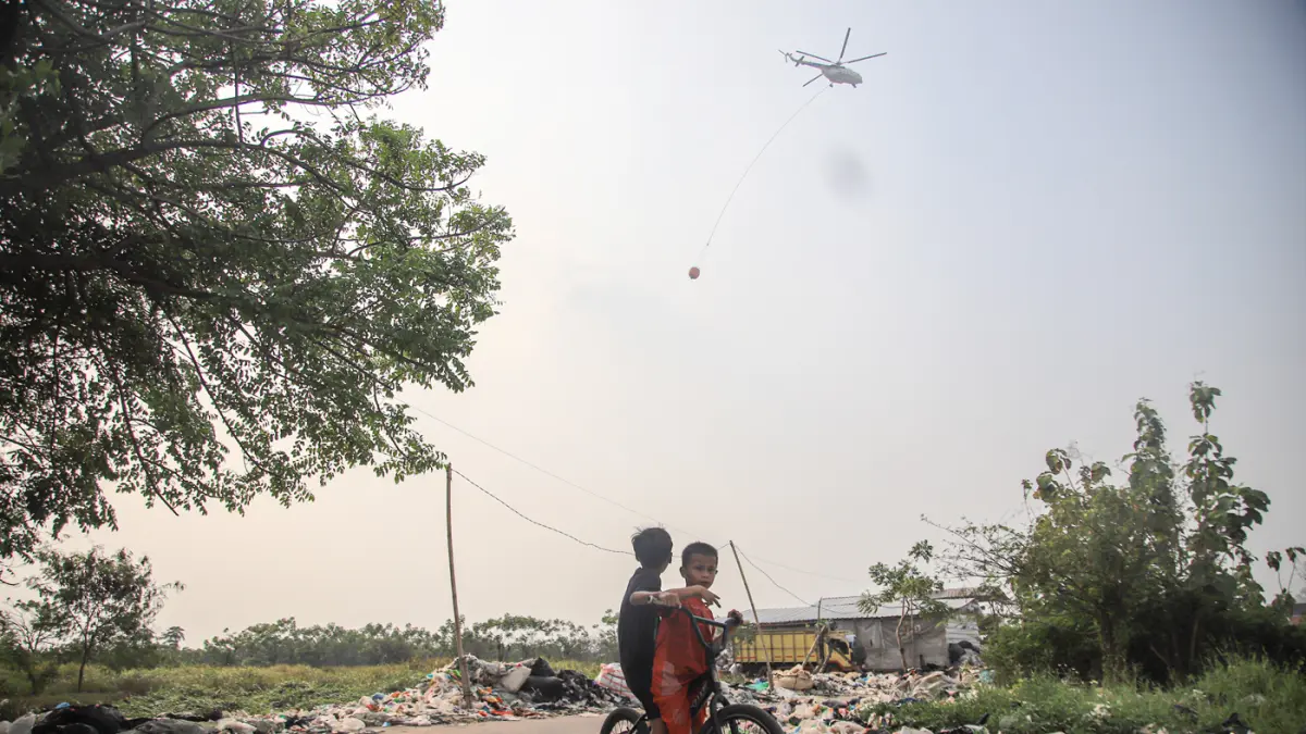 Sejumlah warga beraktifitas ditengah asap kebakaran TPa Jatiwaringin di Desa Tanjakan Mekar, Rajeg, Tangerang, Jumat (03/07/3026). (Hanung Hambara/Jawa Pos)