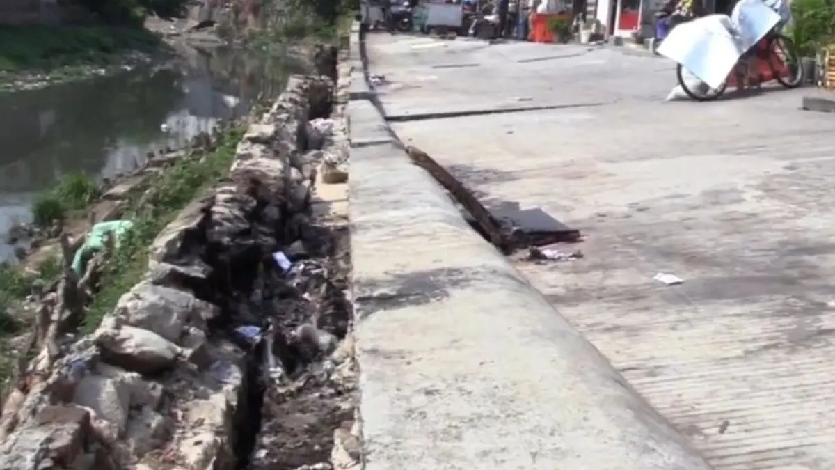 Warga mengeluhkan kondisi jalan amblas di bantaran Kali Pulo Gadung, Jakarta Timur yang semakin meluas selama lima bulan sejak April 2026. (ANTARA) - Image