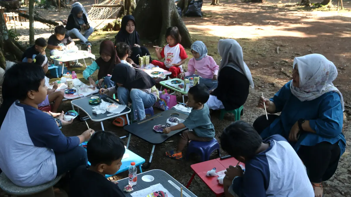 Anak di dampingi orang tua mewarnai topeng pada kegiatan bertajuk Liburan Sehat Ceria Tanpa Handphone di Sanggar Seni dan Budaya Omah Alas, Desa Wisata Kandri, Gunungpati, Semarang, Jawa Tengah, Kamis (9/7/2026). (Nur Chamim/Jawa Pos Radar Semarang)