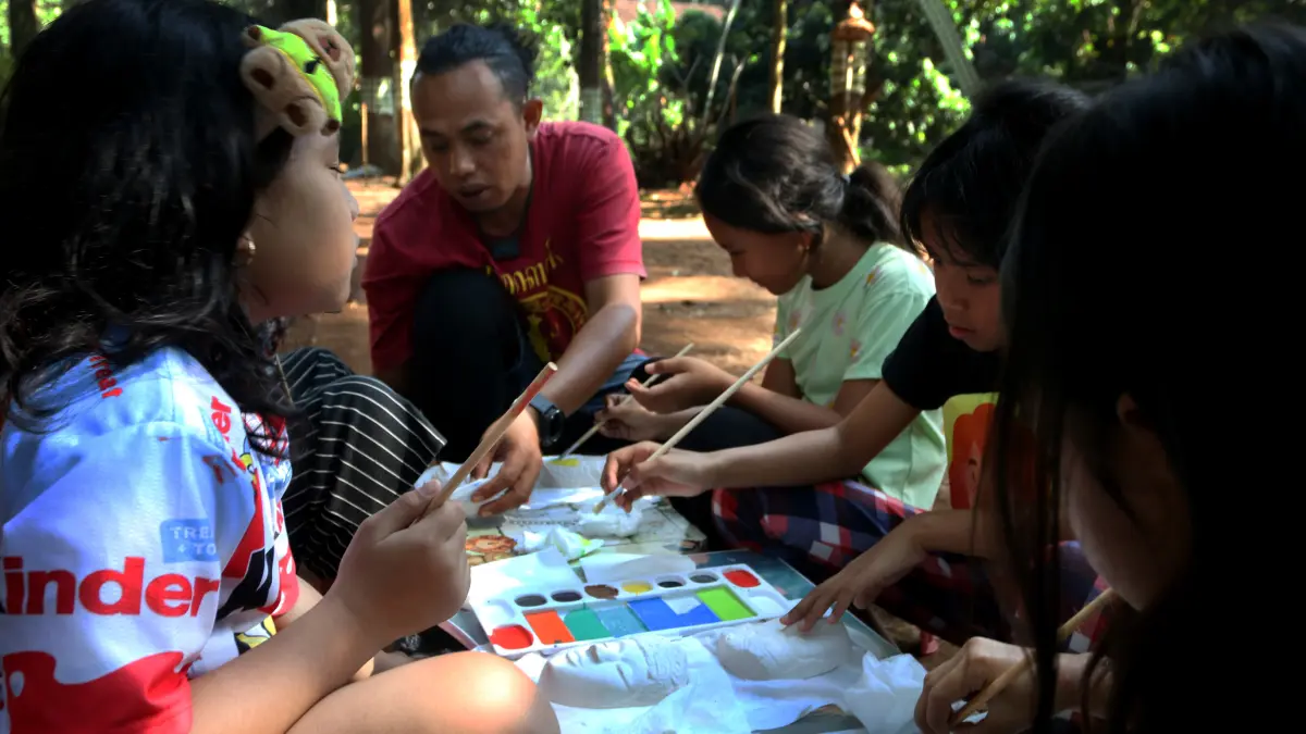Anak di dampingi pemandu mewarnai topeng pada kegiatan bertajuk Liburan Sehat Ceria Tanpa Handphone di Sanggar Seni dan Budaya Omah Alas, Desa Wisata Kandri, Gunungpati, Semarang, Jawa Tengah, Kamis (9/7/2026)