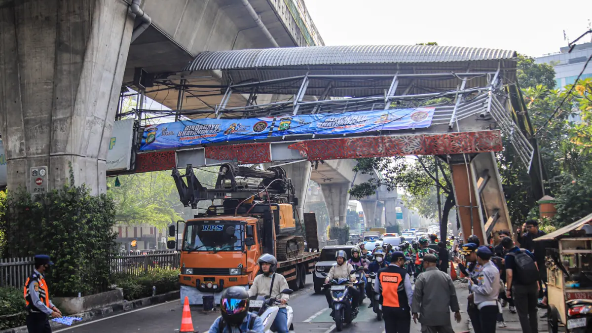 Petugas mengatur kemacetan lalu lintas akibat sebuah truk pengangkut alat berat tersangkut di Jembatan Penyeberangan Orang (JPO) Jalan Tendean, Jakarta, Selasa (14/03/2026). (Hanung Hambara/Jawa Pos)