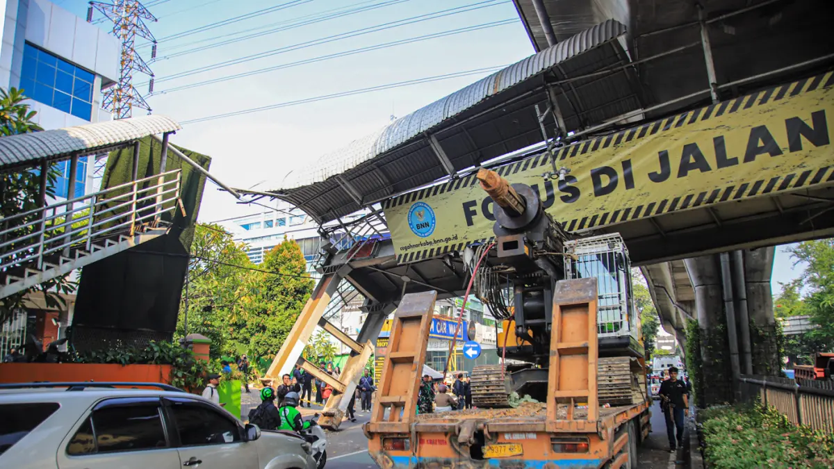 Petugas mengatur kemacetan lalu lintas akibat sebuah truk pengangkut alat berat tersangkut di Jembatan Penyeberangan Orang (JPO) Jalan Tendean, Jakarta, Selasa (14/03/2026). (Hanung Hambara/Jawa Pos)