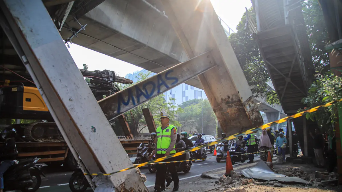 Petugas mengatur kemacetan lalu lintas akibat sebuah truk pengangkut alat berat tersangkut di Jembatan Penyeberangan Orang (JPO) Jalan Tendean, Jakarta, Selasa (14/03/2026). (Hanung Hambara/Jawa Pos)