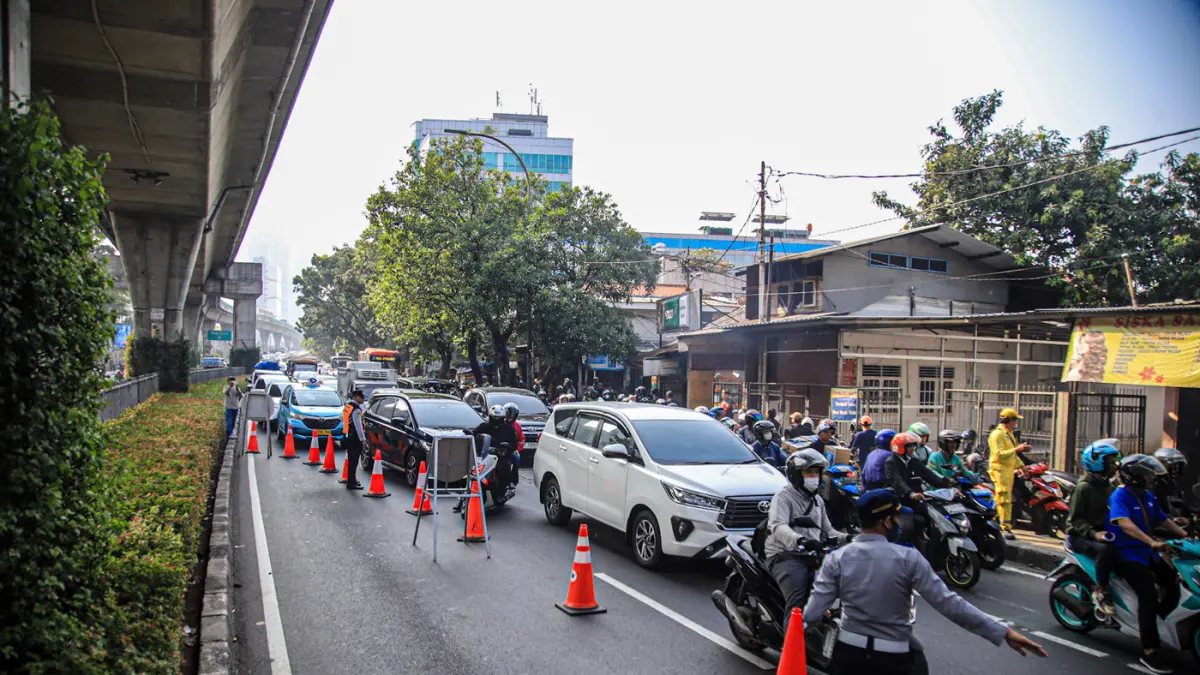 Petugas mengatur kemacetan lalu lintas akibat sebuah truk pengangkut alat berat tersangkut di Jembatan Penyeberangan Orang (JPO) Jalan Tendean, Jakarta, Selasa (14/03/2026). (Hanung Hambara/Jawa Pos)