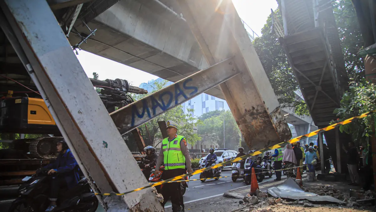 Petugas mengatur kemacetan lalu lintas akibat sebuah truk pengangkut alat berat tersangkut di Jembatan Penyeberangan Orang (JPO) Jalan Tendean, Jakarta, Selasa (14/03/2026). (Hanung Hambara/Jawa Pos)