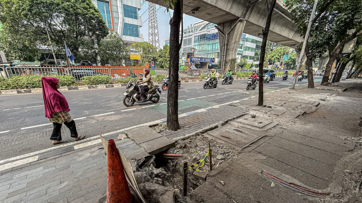 Sejumlah pengguna jalan melintas di bekas JPO yang rusak akibat diatabrak truk di Jalan Tendean, Senin (20/06/2026). (Hanung Hambara/Jawa Pos)