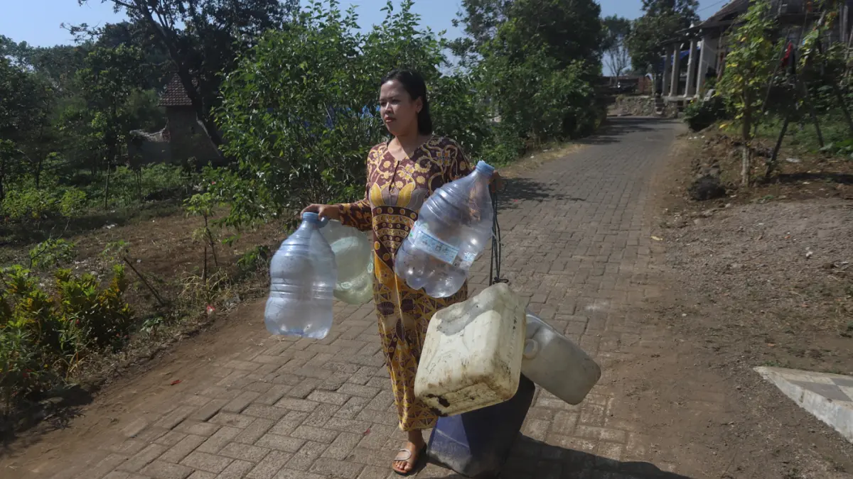 Warga membawa air bersih yang didapatkan dari bantuan Pemerintah di Dusun Kandangan Desa Kunjorowesi Kecamatan Ngoro Kabupaten Mojokerto. Rabu (22/7/2028). (Sofan/ Jawa Pos Radar Mojokerto)