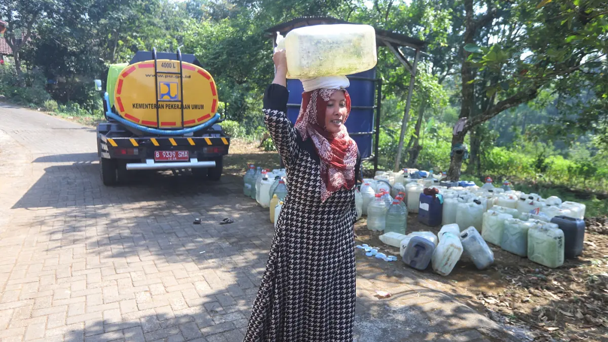 Warga membawa air bersih yang didapatkan dari bantuan Pemerintah di Dusun Kandangan Desa Kunjorowesi Kecamatan Ngoro Kabupaten Mojokerto. Rabu (22/7/2028). (Sofan/ Jawa Pos Radar Mojokerto)