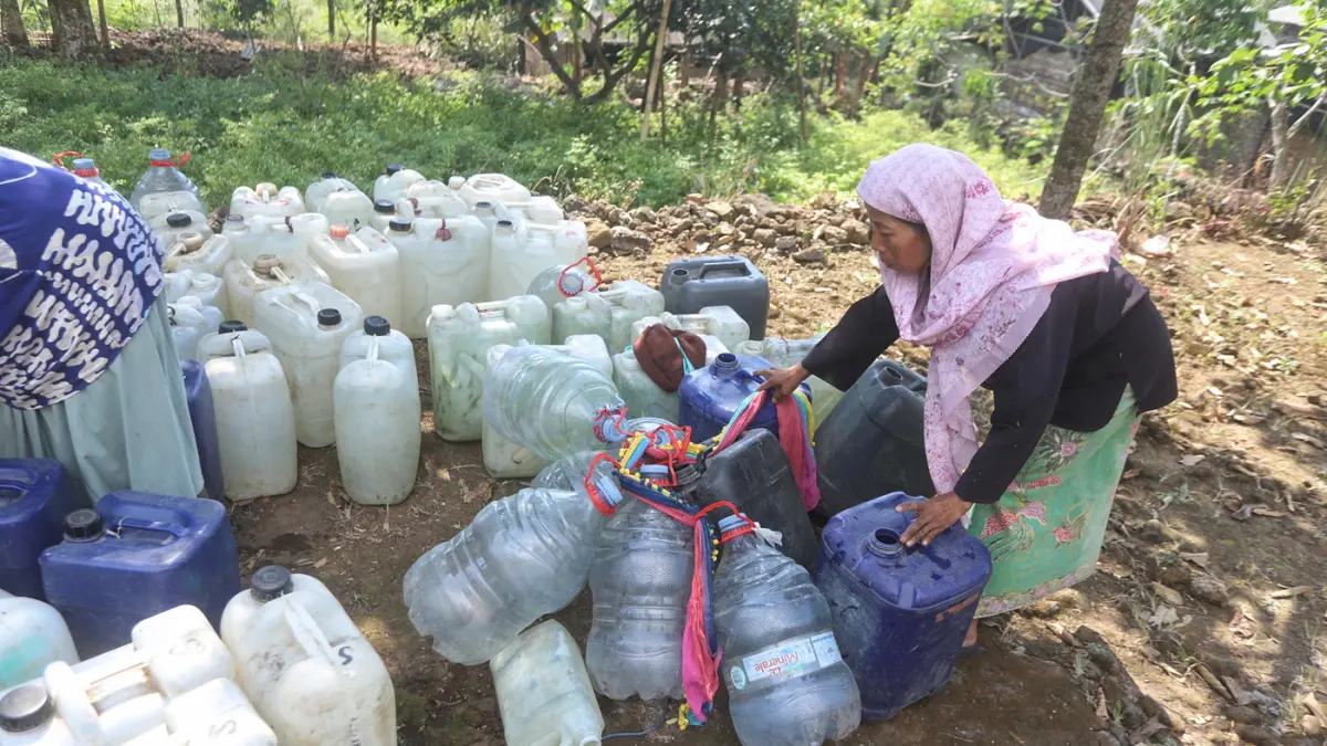 Warga membawa air bersih yang didapatkan dari bantuan Pemerintah di Dusun Kandangan Desa Kunjorowesi Kecamatan Ngoro Kabupaten Mojokerto. Rabu (22/7/2028). (Sofan/ Jawa Pos Radar Mojokerto)