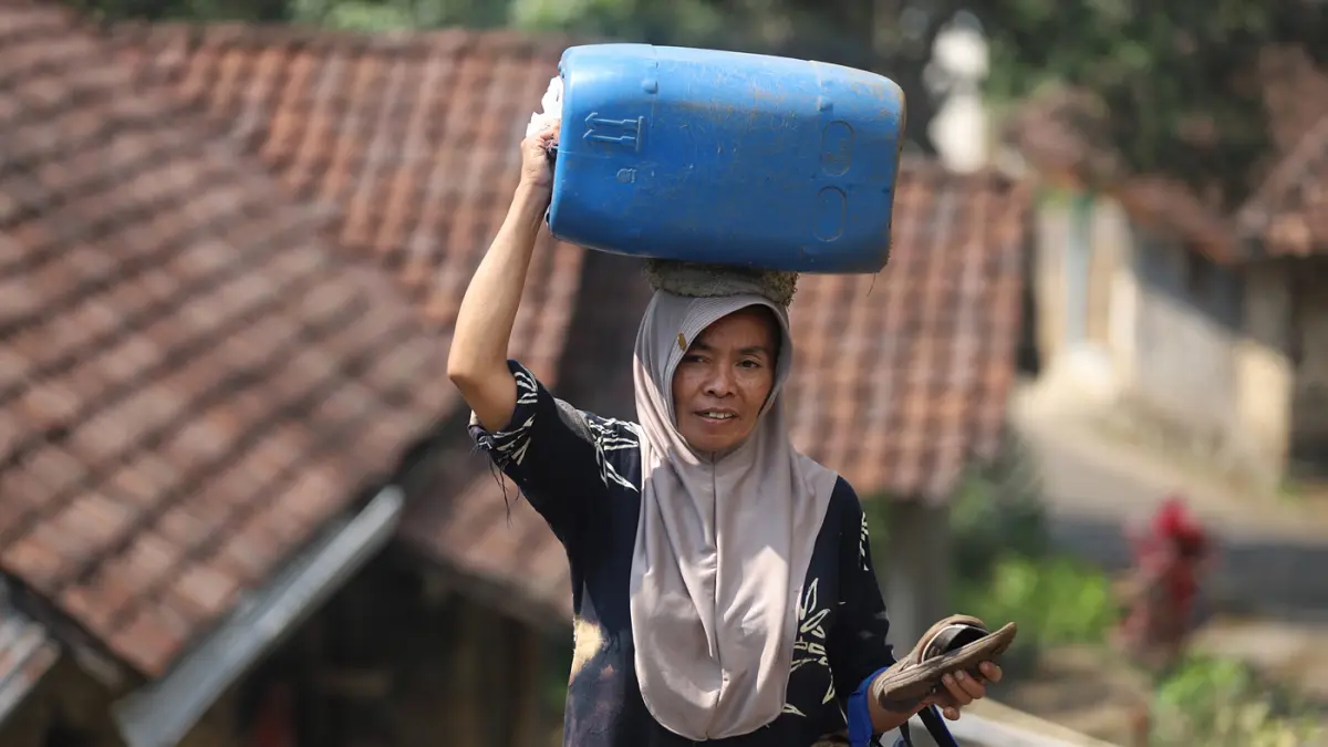 Warga membawa air bersih yang didapatkan dari bantuan Pemerintah di Dusun Kandangan Desa Kunjorowesi Kecamatan Ngoro Kabupaten Mojokerto. Rabu (22/7/2028). (Sofan/ Jawa Pos Radar Mojokerto)