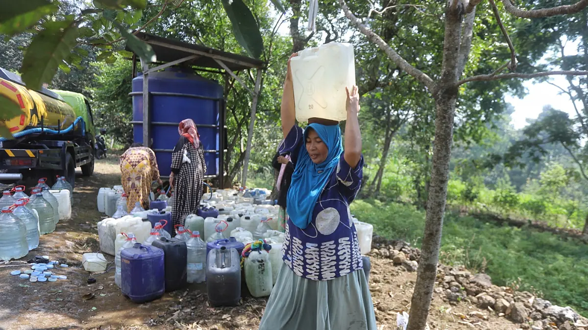 Warga membawa air bersih yang didapatkan dari bantuan Pemerintah di Dusun Kandangan Desa Kunjorowesi Kecamatan Ngoro Kabupaten Mojokerto. Rabu (22/7/2028). (Sofan/ Jawa Pos Radar Mojokerto)