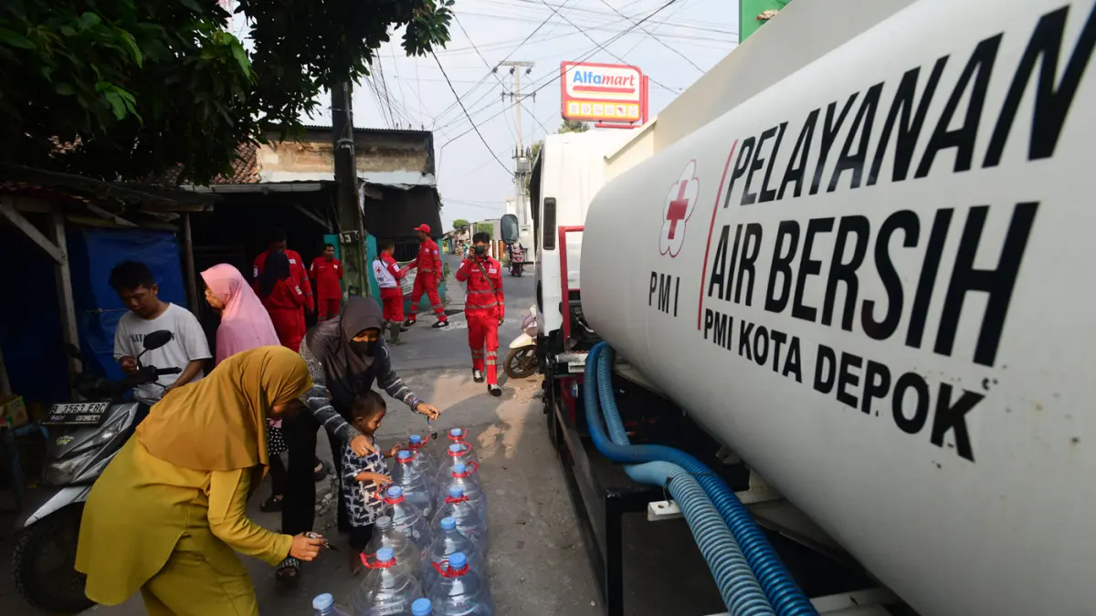Petugas Palang Merah Indonesia (PMI) menyalurkan bantuan air bersih kepada warga terdampak kekeringan di RW 08, Cipayung Jaya, Kota Depok, Jawa Barat, Jumat (24/7/2026). (Dery Ridwansah/ JawaPos.com)