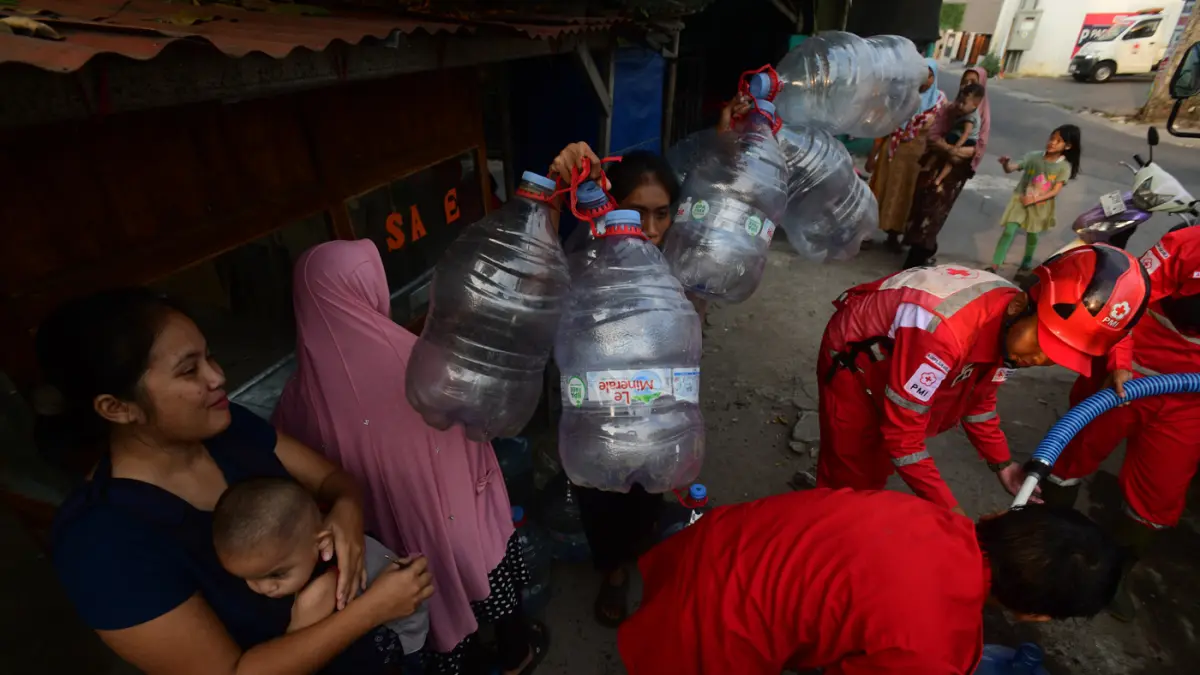 Petugas Palang Merah Indonesia (PMI) menyalurkan bantuan air bersih kepada warga terdampak kekeringan di RW 08, Cipayung Jaya, Kota Depok, Jawa Barat, Jumat (24/7/2026). (Dery Ridwansah/ JawaPos.com)