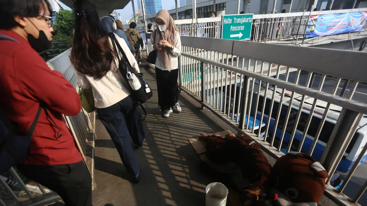 Sejumlah pekerja melintas dekat badut yang tertidur di Kawasan JPO Pancoran, Jakarta Selatan, Senin (20/7/2026). (Dery Ridwansah/ JawaPos.com)