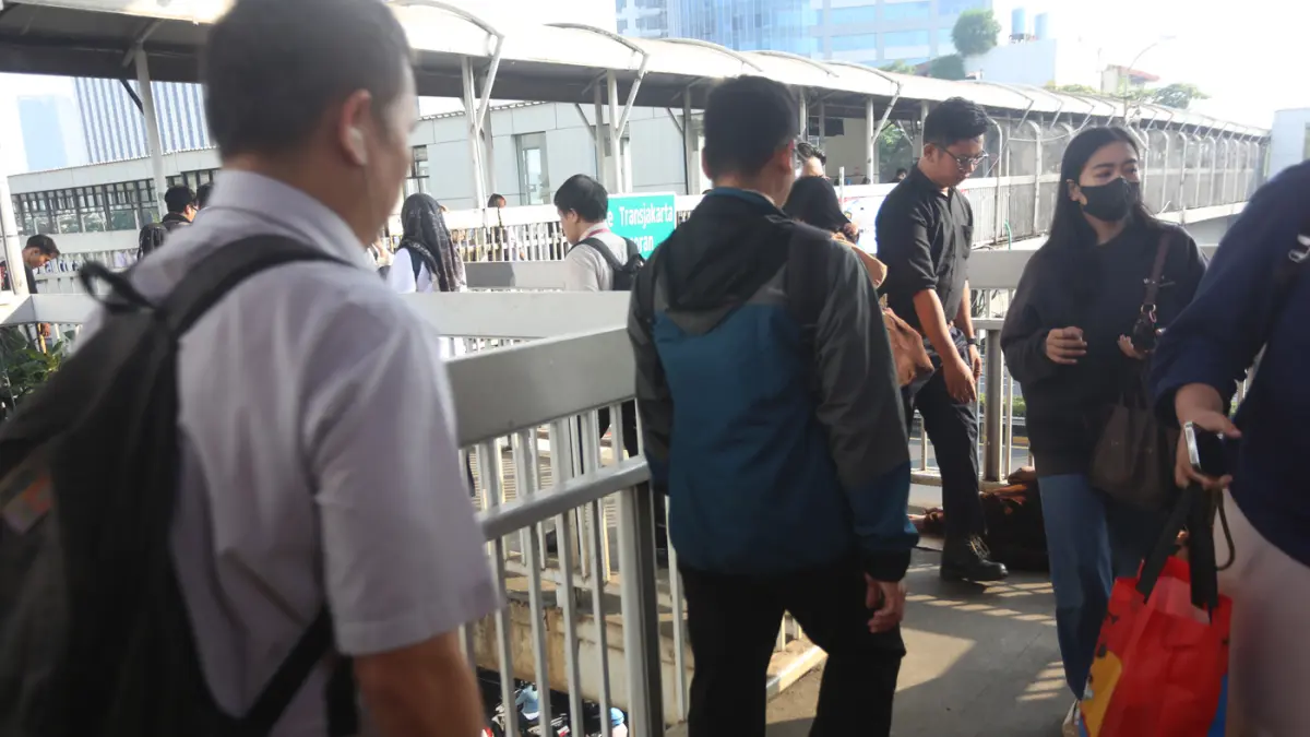 Sejumlah pekerja melintas dekat badut yang tertidur di Kawasan JPO Pancoran, Jakarta Selatan, Senin (20/7/2026). (Dery Ridwansah/ JawaPos.com)