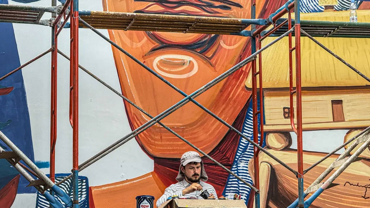 Seniman melukis mural karya kolaborasi tiga seniman, yakni Vitalii Dilkone (Ukraina), Muna Diannur (Indonesia) dan Manuel Skirl (Austria) di salah satu dinding Taman Ismail Marzuki (TIM), Menteng, Jakarta Pusat, Kamis (30/07/2026). (Hanung Hambara/Jawa Po
