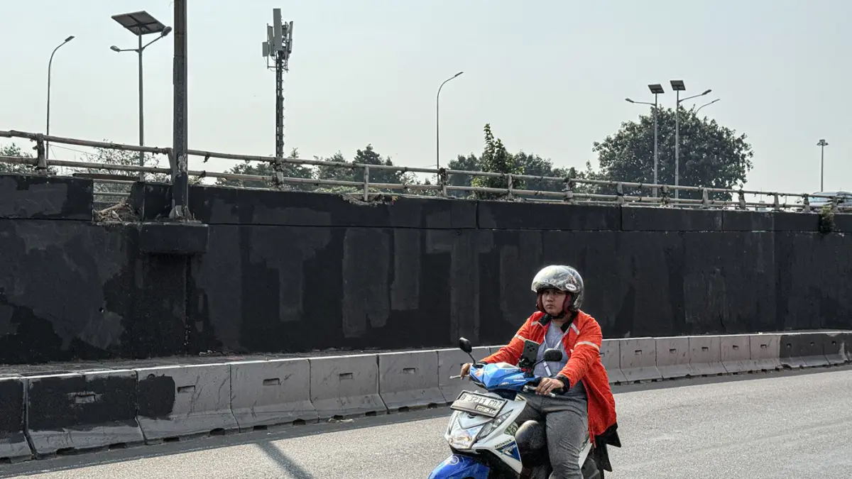 Pengendara melintas di samping Tritura yang telah di hapus di sudut tembok jembatan layang Grogol depan Universitas Trisakti, Jakarta, Minggu (02/08/2026). (Hanung Hambara/Jawa Pos)
