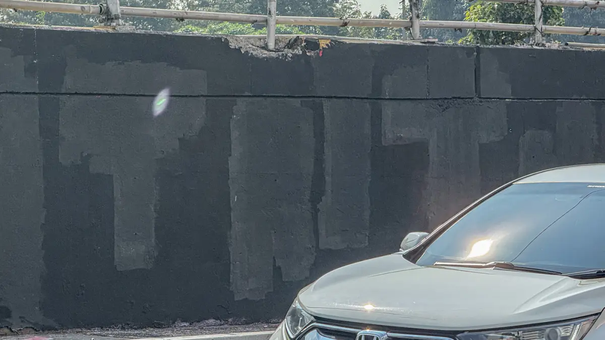 Pengendara melintas di samping Tritura yang telah di hapus di sudut tembok jembatan layang Grogol depan Universitas Trisakti, Jakarta, Minggu (02/08/2026). (Hanung Hambara/Jawa Pos)
