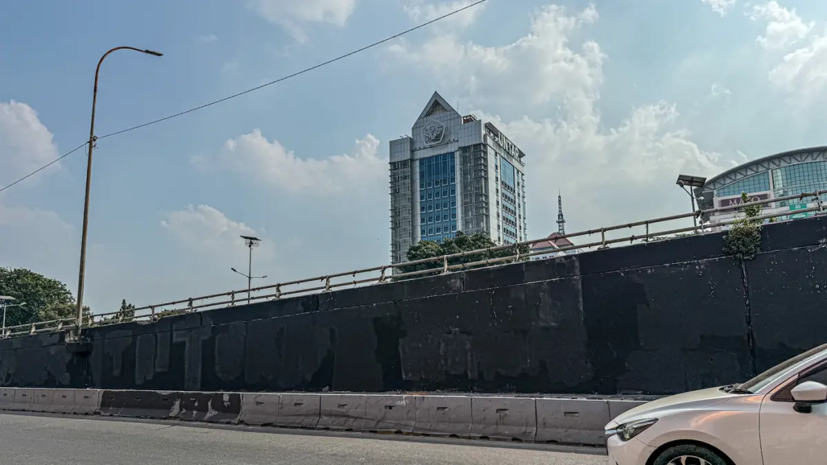 Pengendara melintas di samping Tritura yang telah di hapus di sudut tembok jembatan layang Grogol depan Universitas Trisakti, Jakarta, Minggu (02/08/2026). (Hanung Hambara/Jawa Pos)