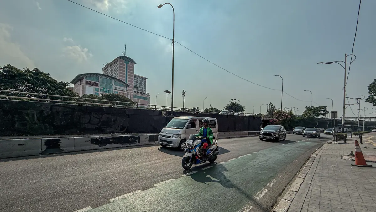 Pengendara melintas di samping Tritura yang telah di hapus di sudut tembok jembatan layang Grogol depan Universitas Trisakti, Jakarta, Minggu (02/08/2026). (Hanung Hambara/Jawa Pos)