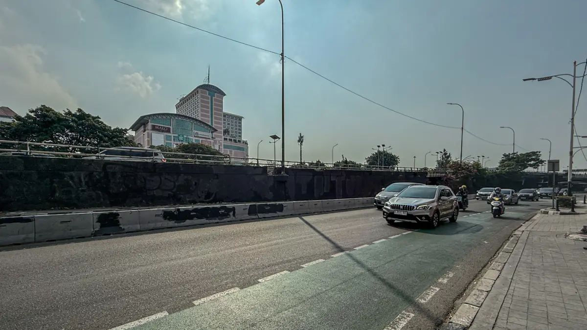 Pengendara melintas di samping Tritura yang telah di hapus di sudut tembok jembatan layang Grogol depan Universitas Trisakti, Jakarta, Minggu (02/08/2026). (Hanung Hambara/Jawa Pos)