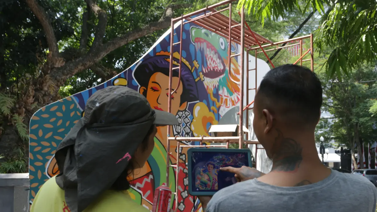Menggunakan teknik free hand dengan cat semprot untuk mengisi bidang mural di gapura Taman Indonesia Kaya,Kota Semarang, Jumat (7/8/2026)