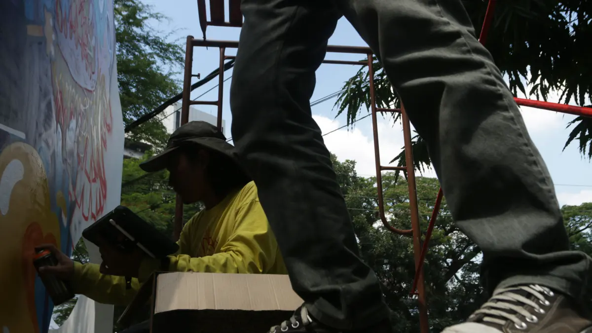 Menggunakan teknik free hand dengan cat semprot untuk mengisi bidang mural di gapura Taman Indonesia Kaya,Kota Semarang, Jumat (7/8/2026)