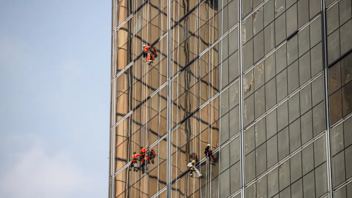 Pekerja memasang kaca gedung di kawasan Jalan M.H. Thamrin, Jakarta, Jumat (07/08/2026). (Hanung Hambara/Jawa Pos)