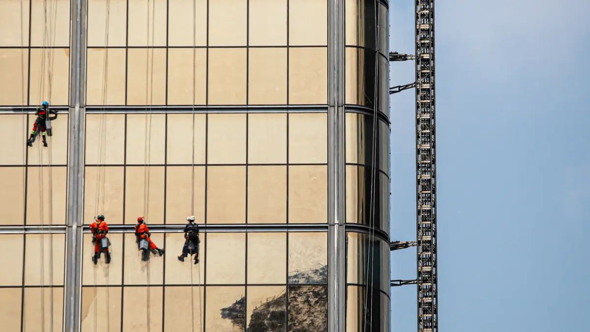 Pekerja memasang kaca gedung di kawasan Jalan M.H. Thamrin, Jakarta, Jumat (07/08/2026). (Hanung Hambara/Jawa Pos)
