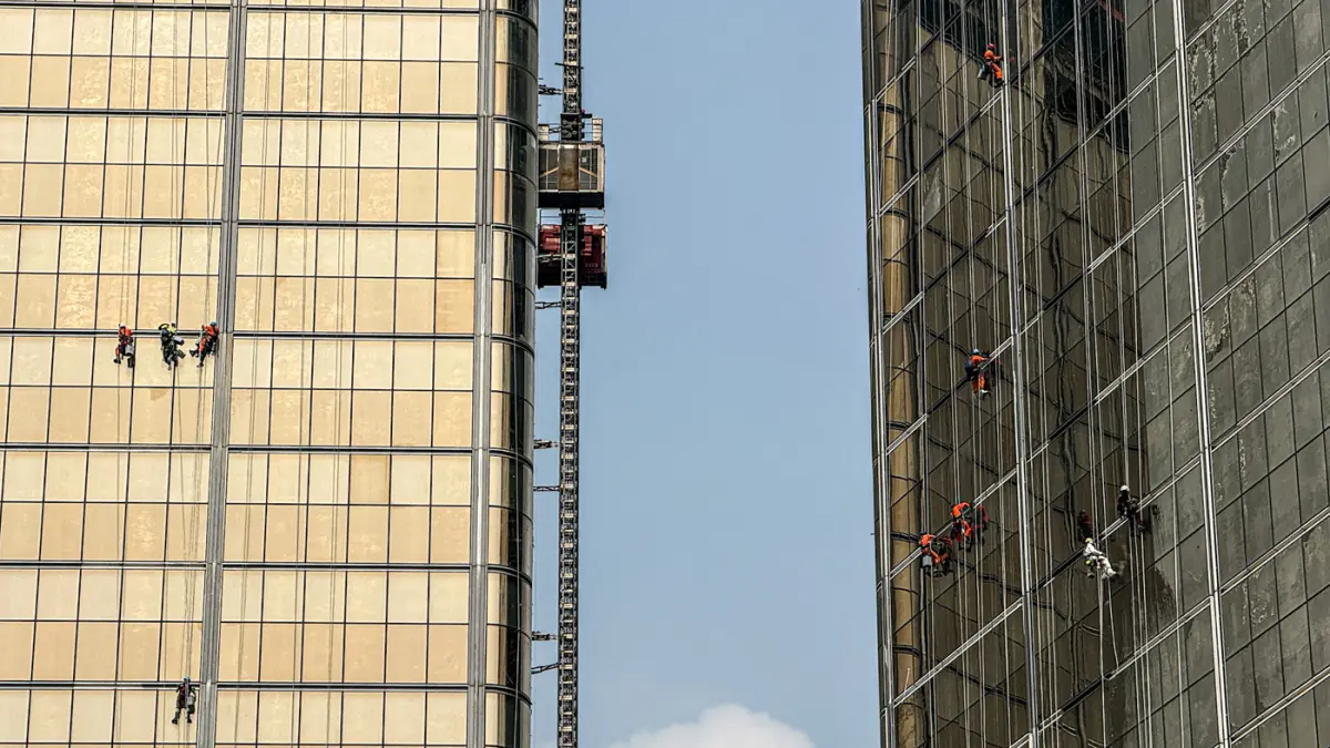 Pekerja memasang kaca gedung di kawasan Jalan M.H. Thamrin, Jakarta, Jumat (07/08/2026). (Hanung Hambara/Jawa Pos)