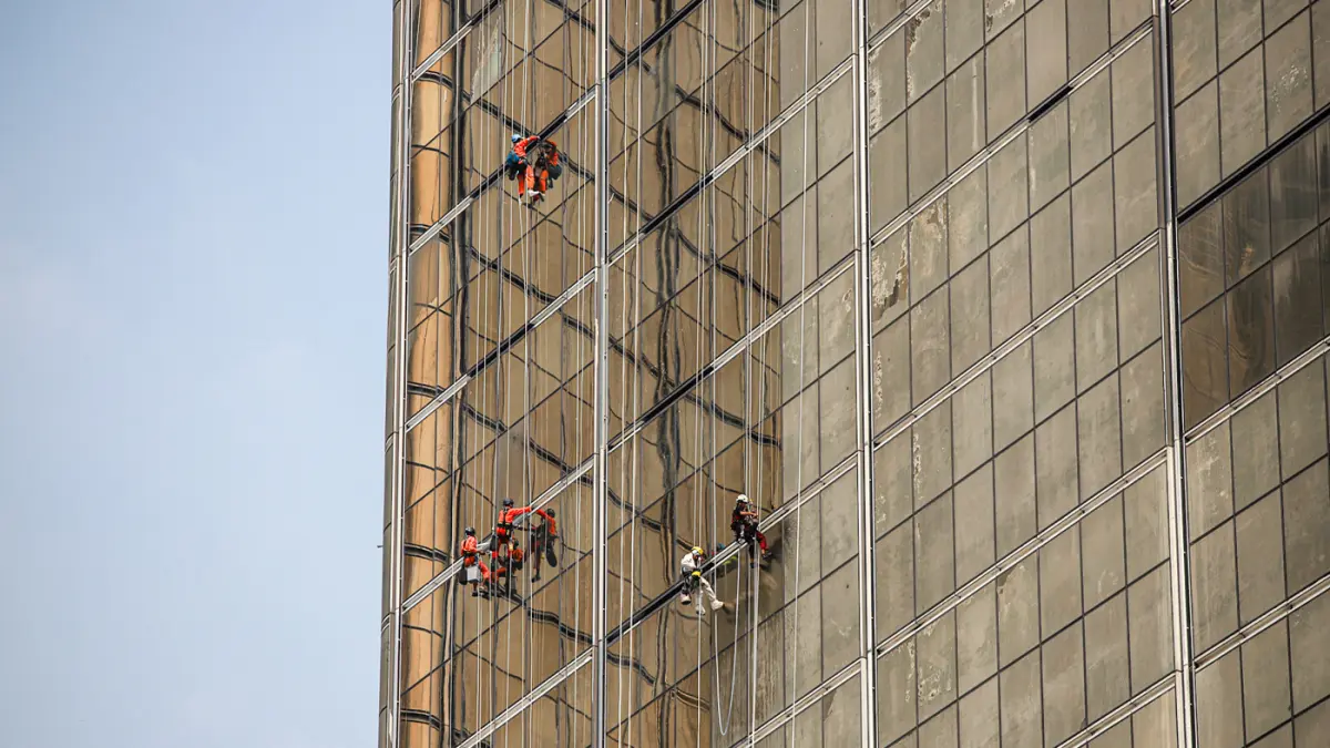 Pekerja memasang kaca gedung di kawasan Jalan M.H. Thamrin, Jakarta, Jumat (07/08/2026). (Hanung Hambara/Jawa Pos)