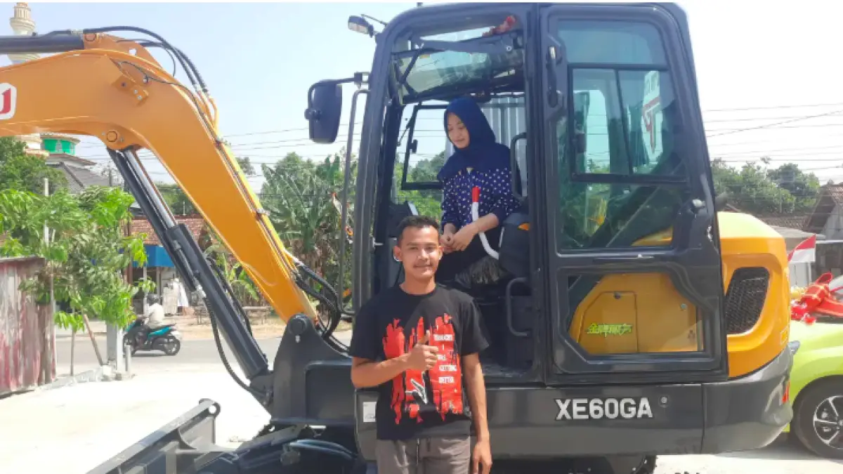 ROMANTIS: Rico dan Laella saat berdiri di samping ekskavator yang dijadikan mahar pernikahan mereka. (INTAN MAYLANI SABRINA/RADAR KUDUS) - Image