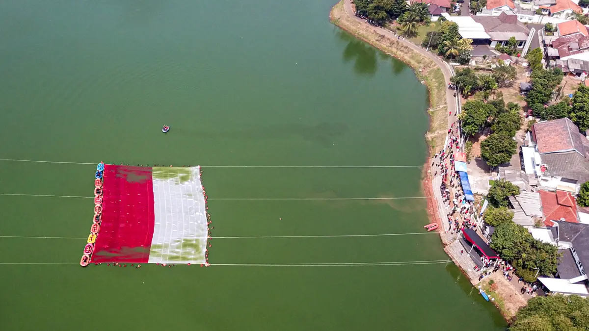 Foto udara relawan membentangkan bendera Merah Putih di Situ Gintung, Tangerang Selatan, Banten, Senin (17/8/2026). (Hanung Hambara/Jawa Pos)