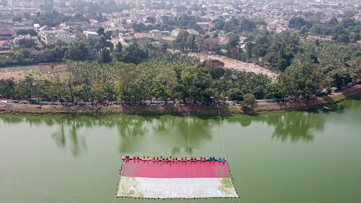 Foto udara relawan membentangkan bendera Merah Putih di Situ Gintung, Tangerang Selatan, Banten, Senin (17/8/2026). (Hanung Hambara/Jawa Pos)